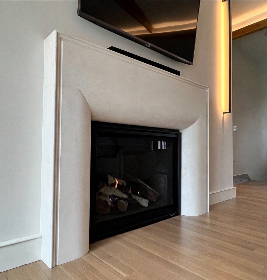 Modern living room with white fireplace surround featuring integrated gas fireplace, wooden flooring, and contemporary ceiling design with ambient lighting